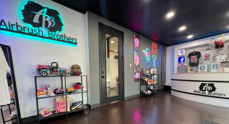 A brightly lit retail store interior specializing in custom airbrushed apparel and accessories.